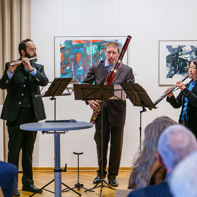 Bild vergr&ouml;&szlig;ern: Drei Musiker mit Instrumenten, davor Menschen