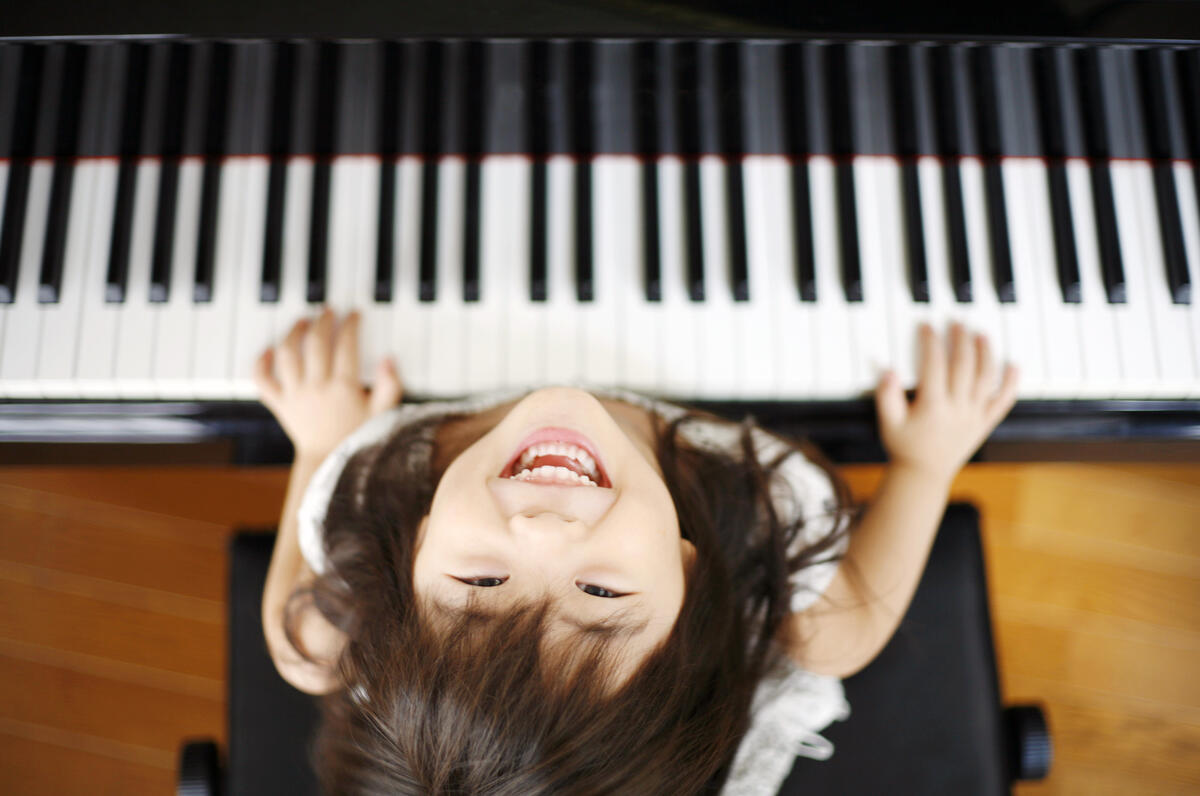 Bild vergrößern: Das Bild zeigt ein Mädchen an einem Klavier.